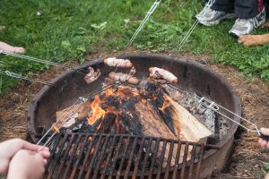 People cooking food over a camp firepit