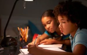 Kids studying under a desk lamp