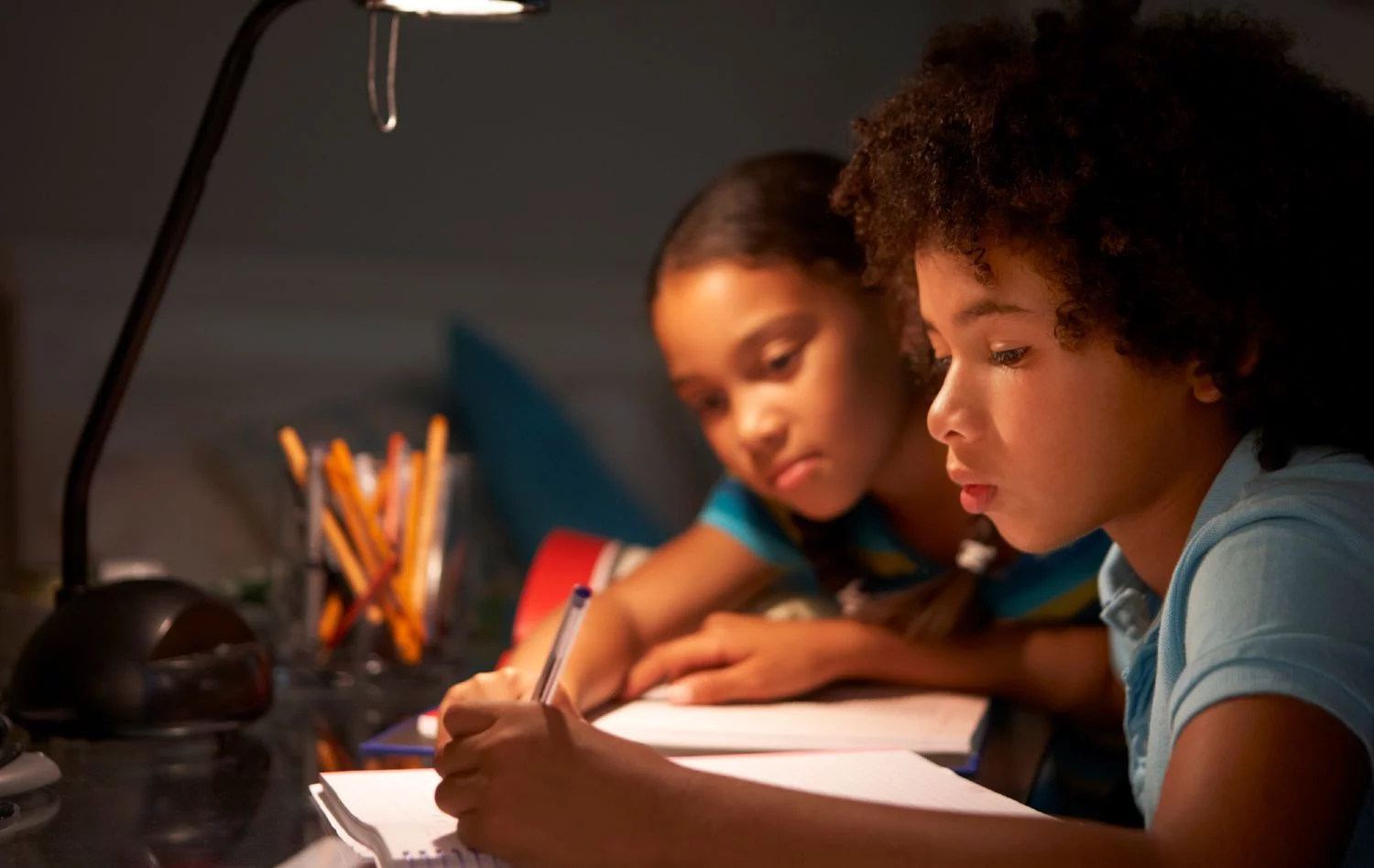 Kids studying under a desk lamp
