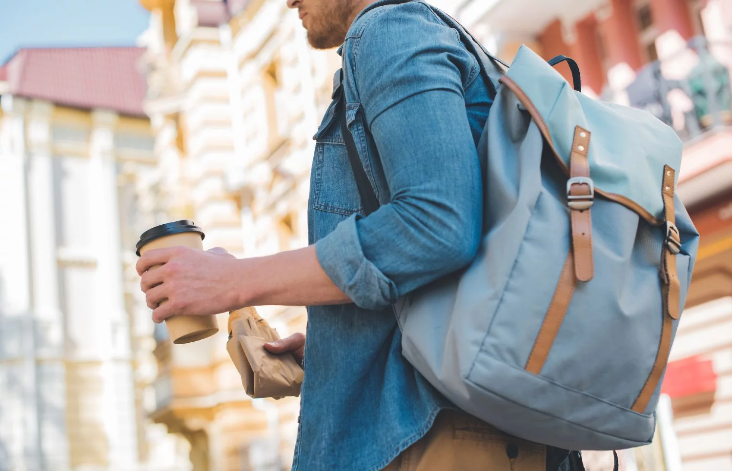 Man commuting through the city with his backpack and a cup of coffee