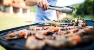Man using tongs to turn food over on a grill